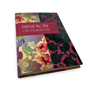 May include: A book titled "Вибіркові Спорідненості" with a colorful floral design on the cover. The book is closed and lying on a white surface.