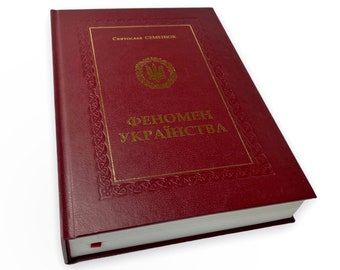 Könnte beinhalten: Ein rotes Hardcover-Buch mit goldenen Lettern und einem goldenen Rand. Der Titel des Buches lautet "Феномен Українства" und der Autor ist "Святослав Семенюк".
