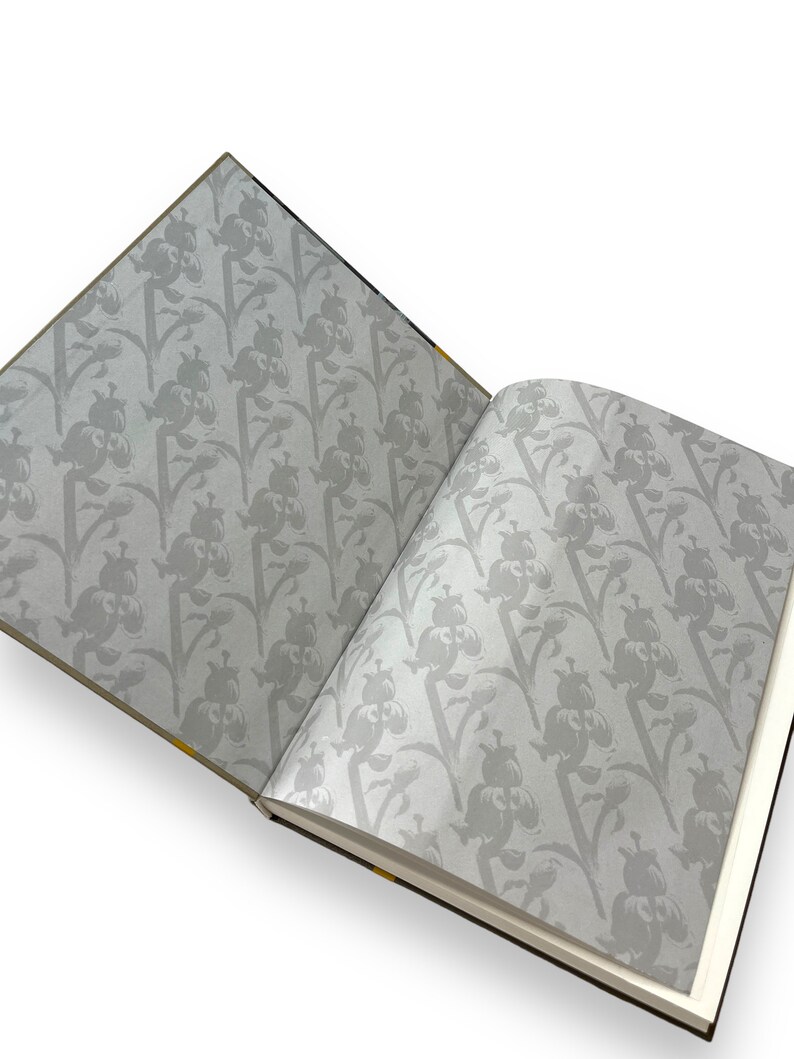 May include: An open book with a floral pattern on the cover and pages. The pattern is a repeating design of gray flowers on a white background.