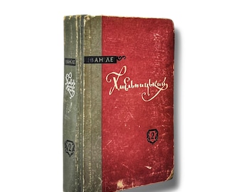 Puede incluir: Un libro rojo y verde con el título "Хлебничка" en escritura cursiva. El libro tiene un aspecto desgastado y vintage.