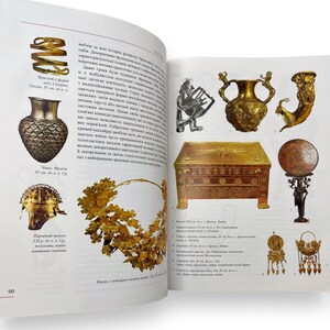 May include: A collection of ancient Greek artifacts, including a golden crown, a golden vase, a golden helmet, a golden box, a golden lyre, and a golden statue. The artifacts are displayed on a white background.