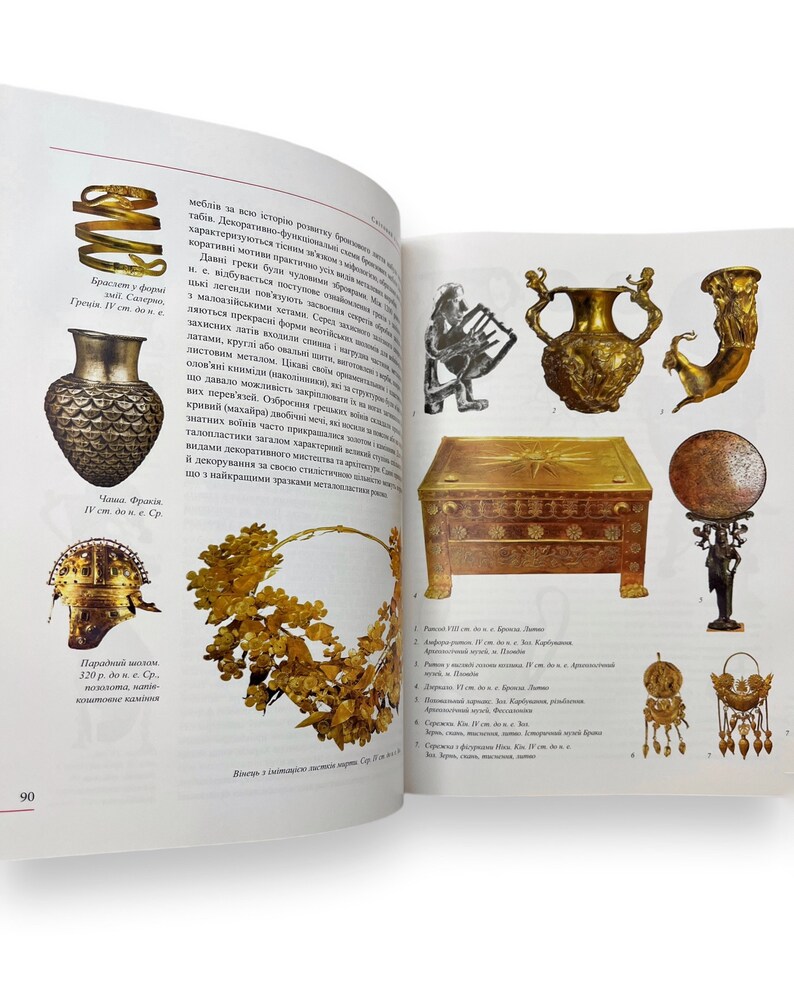 May include: A collection of ancient Greek artifacts, including a golden crown, a golden vase, a golden helmet, a golden box, a golden lyre, and a golden statue. The artifacts are displayed on a white background.