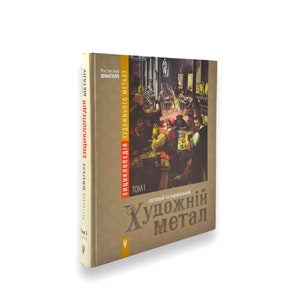 May include: A book titled "Encyclopedia of Artistic Metal: World and Ukrainian" with a brown cover and a painting of people in a tavern. The book is volume one and is written in Ukrainian.