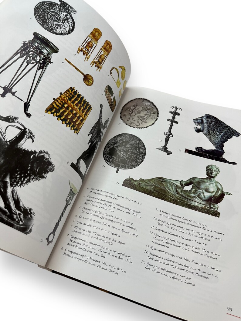 May include: A collection of ancient artifacts, including jewelry, a tripod, a bronze lion, and a statue of a reclining figure. The artifacts are displayed on a white background.