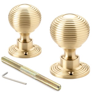 May include: Two brass door knobs with a spherical, ridged design. The knobs are mounted on a circular base with grooves. A threaded rod and an Allen key are also included. The knobs are a classic design.