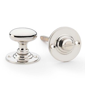 May include: A polished nickel door knob set. The set includes a round knob with a base and a circular plate with a screw. The hardware is designed for a door and has a shiny, reflective surface.