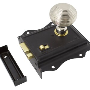 May include: A black door lock featuring a silver, ridged doorknob and brass components. The lock has a decorative, curved edge and includes a separate black strike plate. This door hardware is designed for doors.