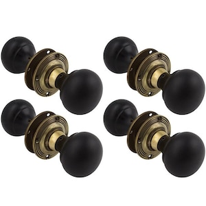 May include: Four black door knobs with brass-coloured circular backplates. The knobs are round and appear to be made of a matte material. The backplates have a decorative, ridged design.