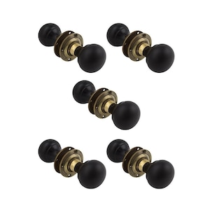May include: Six black door knobs with brass-coloured circular bases are arranged on a white background. Each knob has a rounded, spherical shape. The brass bases have a decorative, aged appearance.
