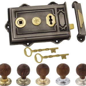 May include: A vintage-style door lock set in dark grey, with brass detailing and two decorative keys. Below are five wooden doorknobs with brass, nickel, and silver-toned bases. Suitable for home restoration projects, this set offers a classic aesthetic.