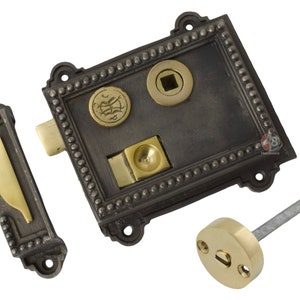 May include: An antique door lock set in dark grey and brass. The rectangular faceplate has a beaded border, two circular brass accents, and a brass latch. A matching strike plate and brass-toned knob are also included.