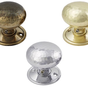 May include: Three round door knobs with a hammered texture. One is dark brass, another is gold, and the third is silver. Each knob has a circular base with screw holes for mounting.
