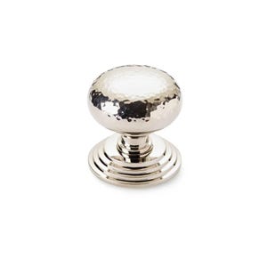 May include: A polished silver cabinet knob with a hammered texture on the spherical handle. The knob sits on a tiered base, reflecting light. Suitable for drawers and cabinets.