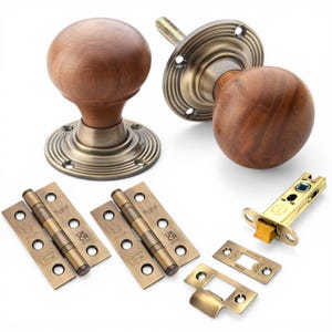 May include: A selection of door hardware featuring two wooden doorknobs with brass fittings, two brass hinges, and a brass door latch. The doorknobs have a brown, spherical wooden design. The hinges and latch are stamped with the word "TUFF".