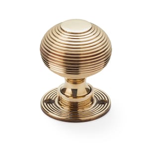 May include: A brass door knob with a spherical design featuring concentric ridges. The knob sits on a circular base with matching concentric grooves. The hardware is a warm gold colour, suitable for interior doors.