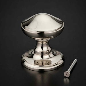 May include: A polished nickel cabinet knob with a smooth, rounded mushroom-shaped head and a flared circular base. The hardware features a reflective, metallic silver finish and includes a single threaded metal mounting screw for installation.