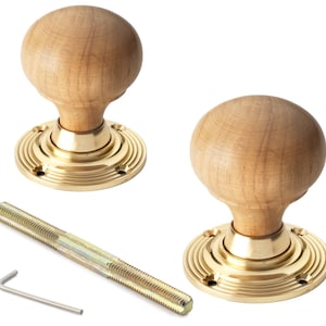 May include: Two wooden door knobs with brass bases, a threaded rod and a hex key. The spherical knobs are light brown, with brass bases featuring concentric circles. The hardware is designed for door installation.