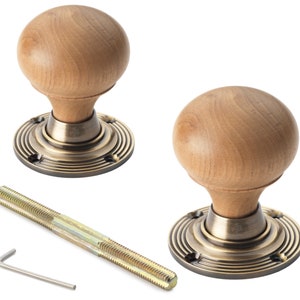 May include: Two wooden door knobs with a spherical design and brass-coloured base plates. The knobs are light brown, and the base plates have a circular grooved pattern. A threaded rod and an Allen key are also included.