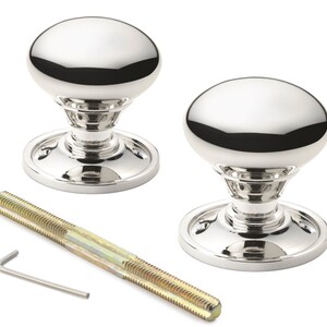 May include: Two polished chrome door knobs with an oval design, set on a circular base. A threaded rod and an Allen key are included. The hardware has a reflective surface, suitable for interior doors.