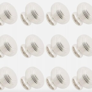 May include: Twelve silver cabinet knobs are displayed. Each knob features a ridged, rounded top and a small, circular base. The knobs are arranged in three rows of four against a white backdrop. The knobs are made of metal.