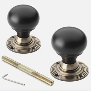 May include: Two black door knobs with a round shape and a bronze-coloured base. The base has a circular design. A long screw and an Allen key are also included.