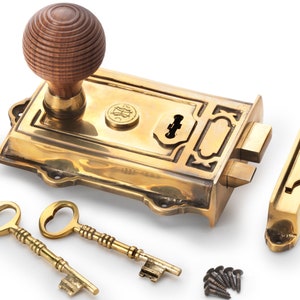 May include: A brass door latch set featuring a wooden knob, two ornate keys, and a strike plate. The rectangular latch has decorative detailing and a keyhole. Small screws are included.