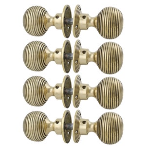 May include: Four brass door knobs with a ribbed, spherical design. Each knob has a matching backplate and connecting hardware. The knobs are a warm, antique gold colour, and are arranged in two rows of two.