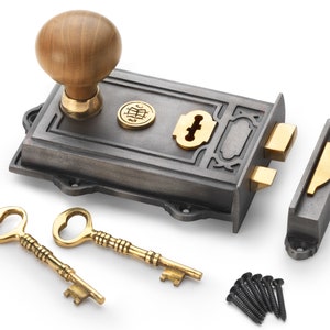 May include: A cast iron door lock set with a wooden knob, brass accents, and two ornate keys. The set includes a strike plate and mounting screws, suitable for vintage or antique doors.