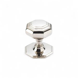 May include: A polished, silver-toned door knob with an octagonal design. The knob has a faceted top and base, connected by a slender, decorative stem. The hardware is set against a plain white background.