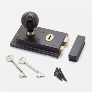 May include: A black door lock set with a round, grooved knob, a keyhole, and two keys. The set includes a strike plate and screws. The hardware is made of metal and has a classic design.