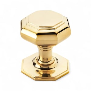 May include: A polished brass door knob with an octagonal design. The knob has a shiny, reflective surface and a classic, elegant appearance. The base and top of the knob are also octagonal, creating a cohesive design.