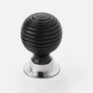 May include: A black, spherical cabinet knob with a grooved texture. The knob sits atop a short, black stem and a shiny, silver-coloured base. This decorative hardware is suitable for drawers and cabinets.