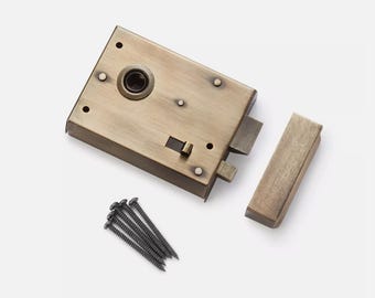 Op de afbeelding: Een messing deurslot in vintage-stijl met een rechthoekige behuizing, een aparte grendel en een set schroeven. Het slot heeft een aangetaste afwerking, wat duidt op een antieke uitstraling. Deurbeslag.