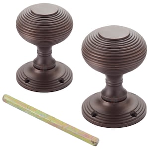 May include: Two bronze door knobs with a ribbed, spherical design. Each knob sits on a circular base with three screw holes. A metal rod is included for installation. The hardware has a vintage aesthetic.