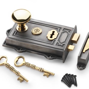 May include: A cast iron door lock set with a brass knob, keyhole, and strike plate. Includes two ornate brass keys and black screws. The lock has a dark grey finish with brass accents.