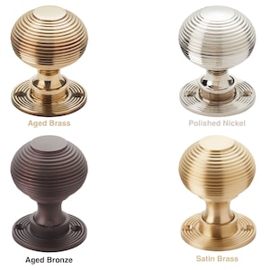 May include: Four door knobs in various finishes: aged brass, polished nickel, aged bronze, and satin brass. Each knob features a spherical design with concentric ridges and a circular base. Text below each knob indicates the finish.
