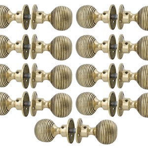 May include: A set of antique brass door knobs. Each knob features a ribbed, spherical design and is paired with a matching backplate. The hardware has a warm, golden hue, suggesting an aged finish. The knobs are set against a white background.