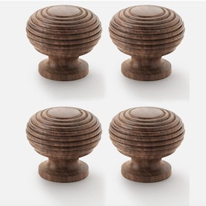 May include: Four wooden cabinet knobs with a round, grooved design. The knobs are a warm brown colour and have a classic, timeless look. These decorative knobs are perfect for adding a touch of elegance to any furniture piece.