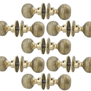 May include: Ten brass door knobs are displayed. Each knob features a ribbed, spherical design and a matching circular backplate. The knobs are arranged symmetrically against a white background, highlighting their classic hardware aesthetic.