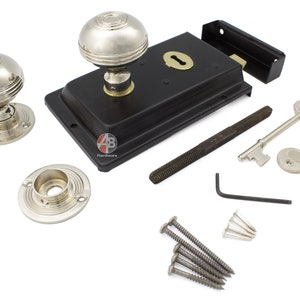 May include: A complete door lock set featuring a black rectangular lock body, two silver-toned doorknobs, two keys, and mounting hardware. The set includes a threaded rod, an Allen key, and screws. The doorknobs have a round, grooved design.
