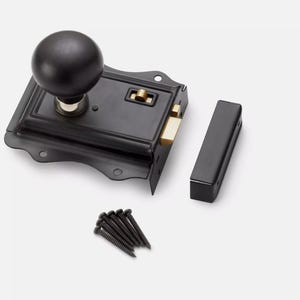 May include: A black door latch set with a round knob, strike plate, and screws. The latch mechanism has a brass-coloured component. The set is designed for door hardware and home improvement projects.