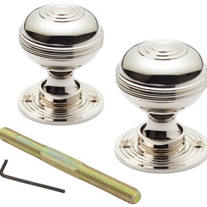 May include: Two polished nickel door knobs with a round, ridged design. Each knob sits on a circular base with screw holes. A threaded rod and an Allen key are included.