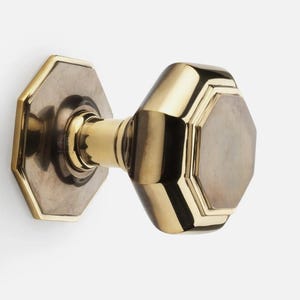 May include: A brass octagonal door knob with a polished finish. The knob features a central handle and a decorative backplate, showcasing a classic design. The hardware is designed for interior doors.