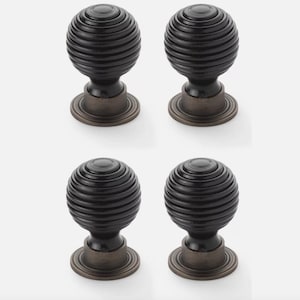 May include: Four dark bronze cabinet knobs. Each knob features a ribbed, spherical design, with a circular base and a rounded top. These knobs are suitable for adding a touch of elegance to furniture, with a classic design.