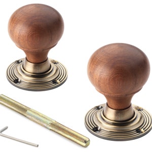 May include: Two wooden door knobs with a dark brown, spherical design. They sit on a brass-toned base with a circular pattern. A threaded rod and an Allen key are also included.