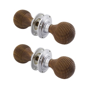 May include: Two wooden door knobs with a ribbed design and a polished chrome base. The knobs are a warm brown colour and have a rounded shape. The base is circular with small holes for mounting.