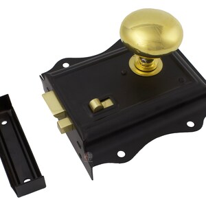 May include: A black door latch with a gold-coloured knob and brass-coloured latch components. The latch has a decorative, curved edge and includes a separate black strike plate. Door hardware.