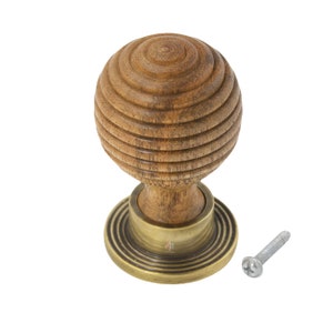 May include: A wooden door knob with a spherical design and a brass base. The knob is made of light brown wood with a grooved pattern. A silver screw is next to the knob. The knob is designed for use on doors and cabinets.