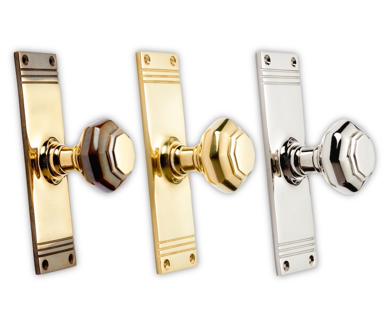 May include: Three door knobs with rectangular backplates. The knobs have an octagonal shape. The first knob is brass with a brown and tan knob. The second knob is brass with a gold knob. The third knob is silver with a silver knob.