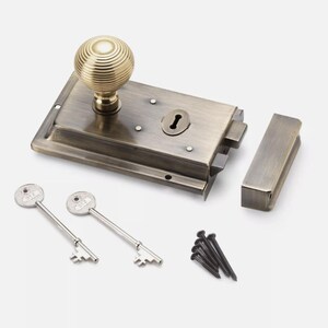 May include: A vintage door latch set featuring a brass knob, a rectangular latch, a strike plate, two keys, and a set of black screws. The metal has a bronze finish. Suitable for home renovation projects and interior design.